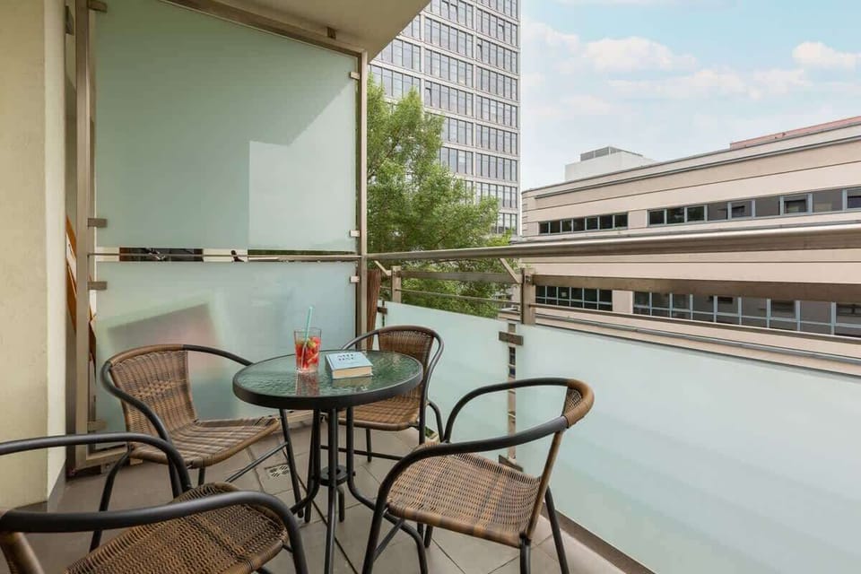 A balcony view showing a small table with chairs, offering a cozy space for outdoor dining, overlooking the city.