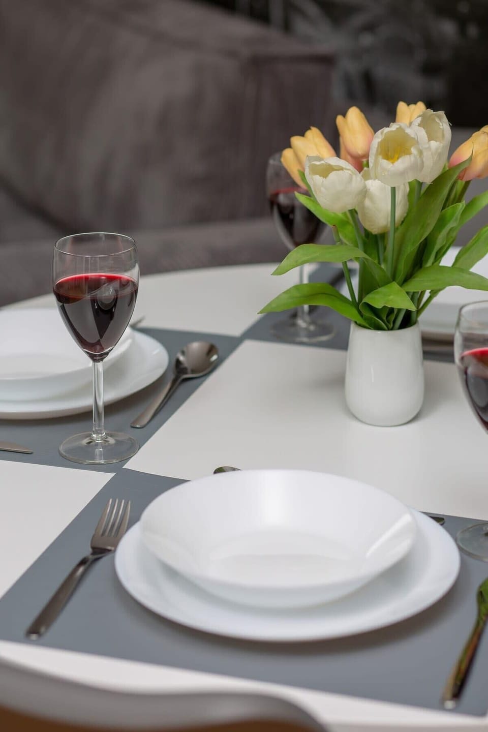A close-up of a dining table with a neatly arranged place setting, including a glass of wine and flowers.
