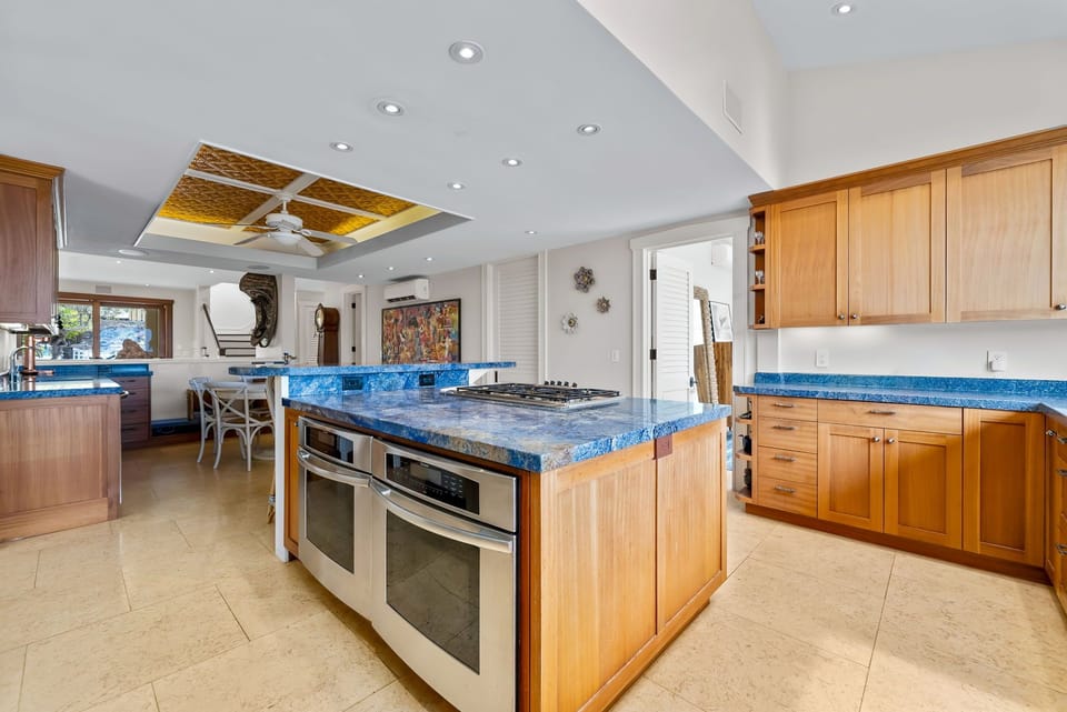 You'll love cooking in this spacious kitchen with its stunning blue countertops, large center island with gas range, double ovens, and warm wood cabinetry that invites your culinary creativity.