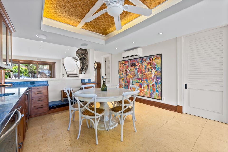 The breakfast nook, where a striking woven ceiling detail and vibrant artwork create an inviting space for your tropical meals and morning coffee rituals.