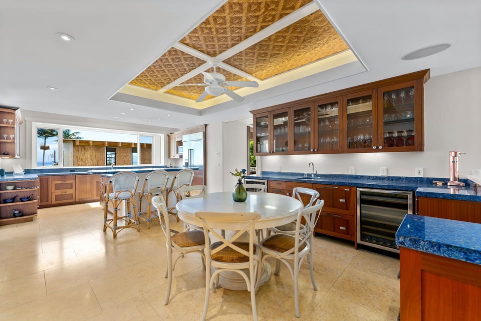 Imagine gathering around this elegant dining table in your spacious gourmet kitchen, with rich wood cabinetry, gleaming blue granite counters, and stunning tray ceiling accents creating a warm, inviting space for your meals.