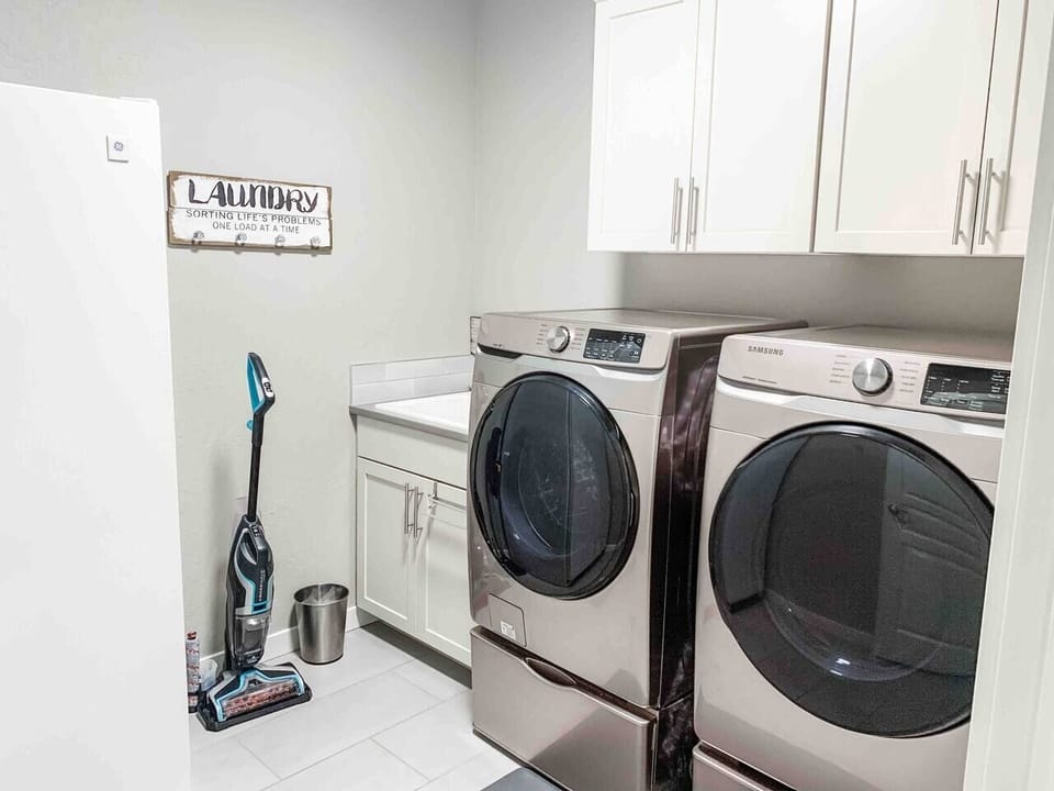 Laundry room features a sink, electric Samsung washer and dryer, and deep freezer 