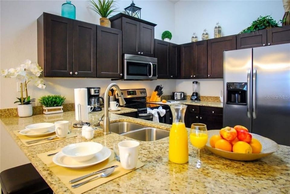 Fully-equipped modern kitchen with stainless steel appliances, granite counters