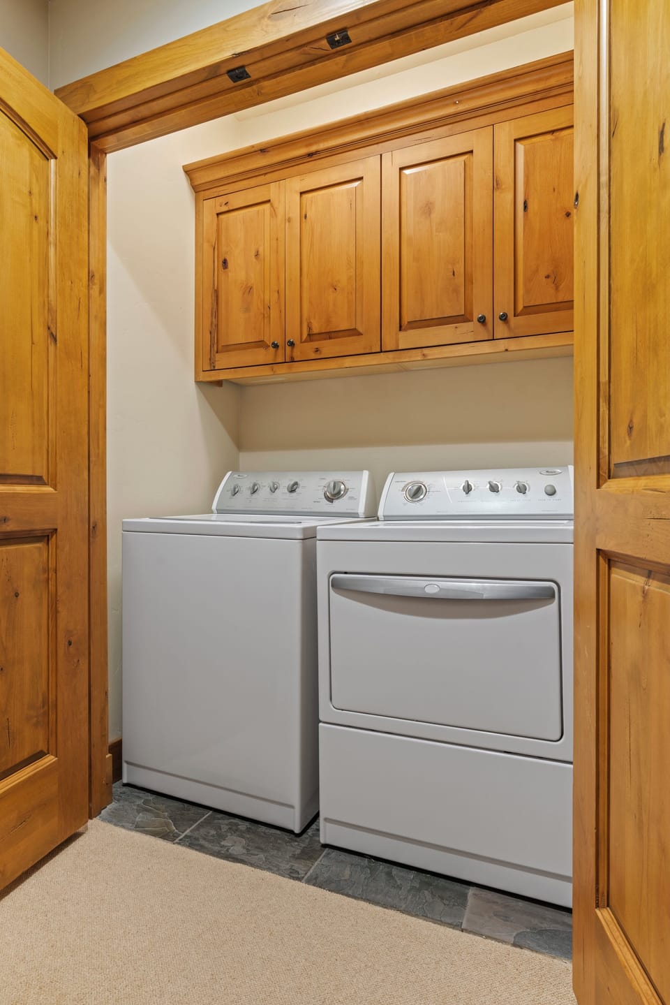 Your own private laundry nook awaits, complete with full-size washer and dryer nestled within beautiful custom cabinetry. The warm wood finishes create a cozy, home-like atmosphere.