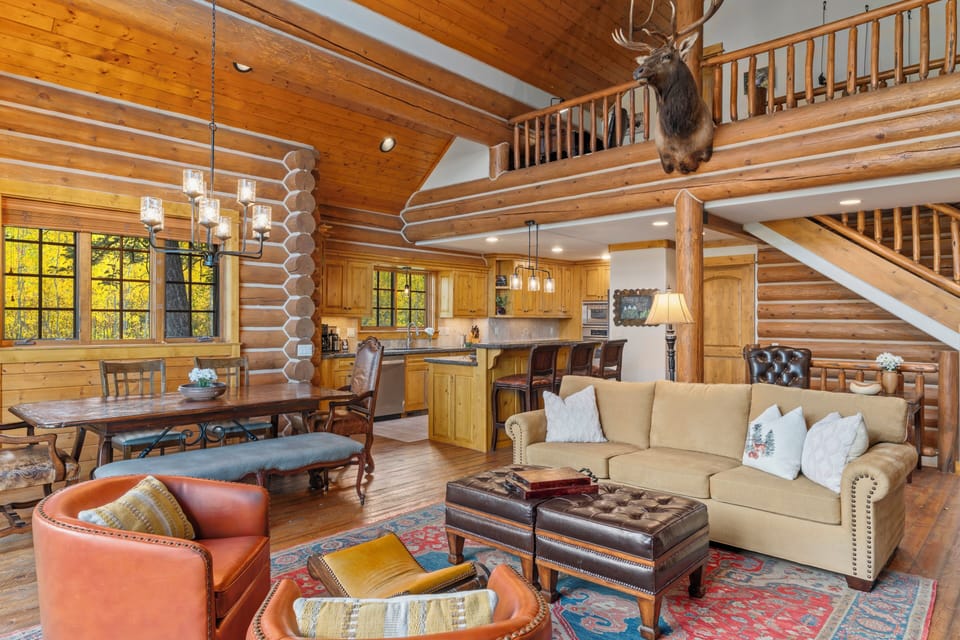 Step into your rustic mountain retreat where warm log walls and soaring ceilings create the perfect blend of cozy comfort and grandeur for your getaway.