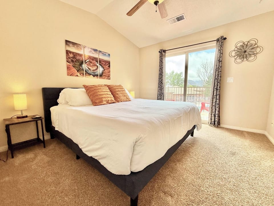 Spacious king bedroom with vaulted ceilings, cozy decor, and private balcony overlooking Kanab's scenic hills.