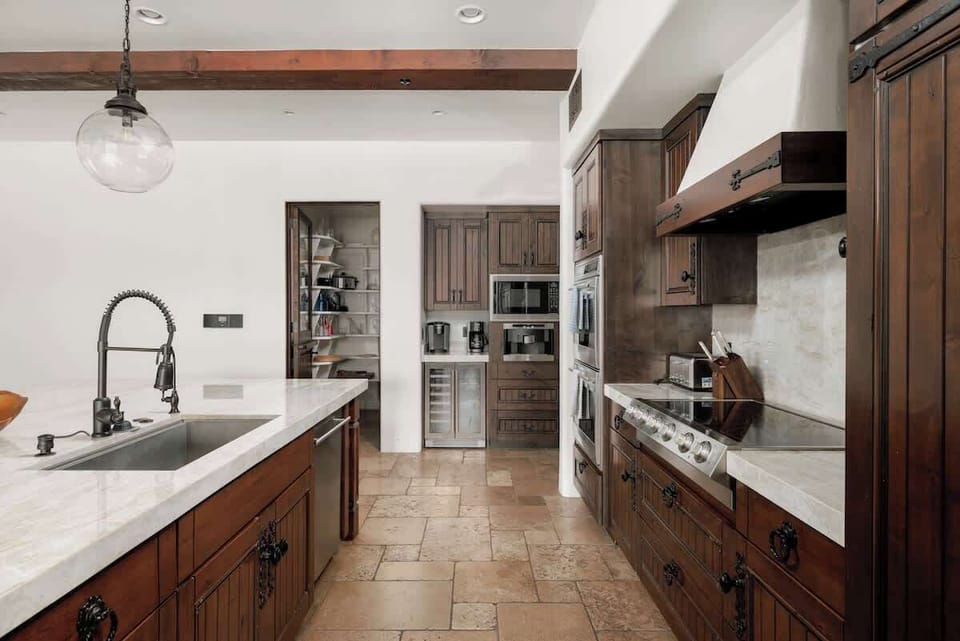 Prepare your favorite meals in this beautifully appointed kitchen, featuring rich wood cabinetry, marble countertops, and top-of-the-line appliances designed for your culinary adventures.