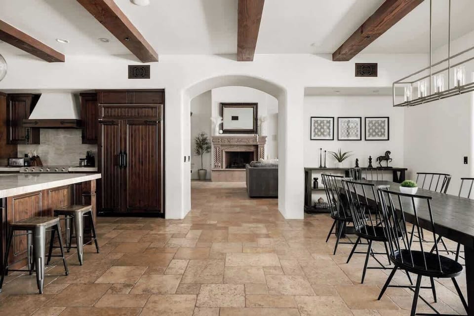 Gather around your spacious dining table under rustic beamed ceilings, where the open-concept design flows seamlessly into a stylish kitchen, perfect for shared meals and memorable conversations.