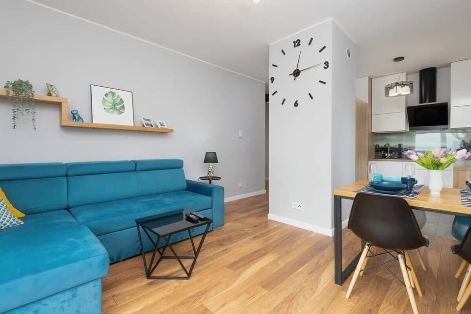 A stylish living room featuring a wall-mounted TV, a light blue sofa, and a small coffee table, perfect for relaxation.