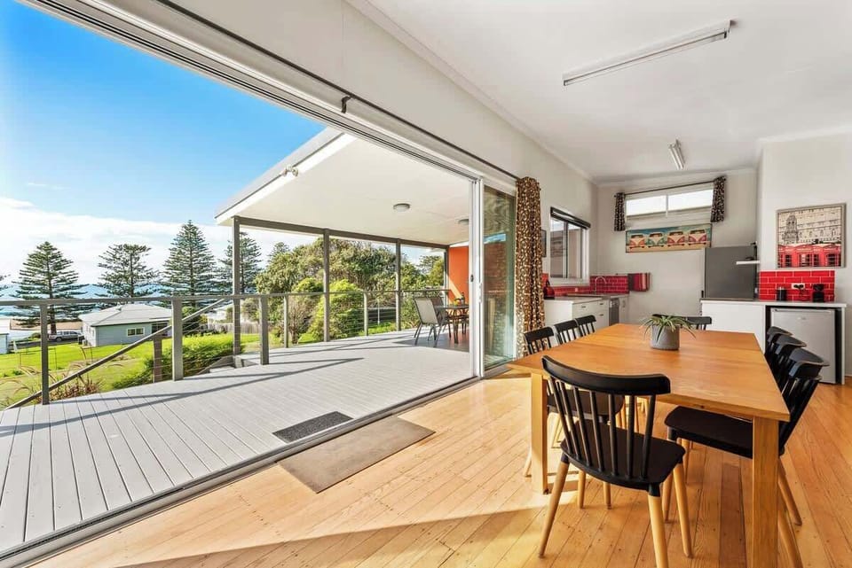 Sunny open plan living and dining area with cosy wood fire and beautiful ocean views.