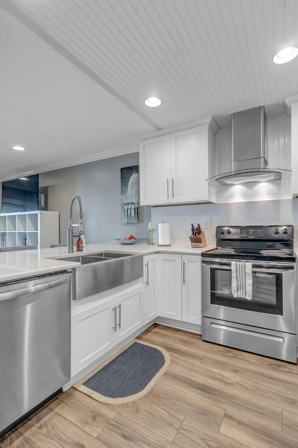 - Modern kitchen boasts a deep farmhouse sink, sleek countertops, and stainless stove
- Crisp white cabinets and under cabinet lighting enhance the clean design
- Perfect space for prepping meals or enjoying casual bites at the bar