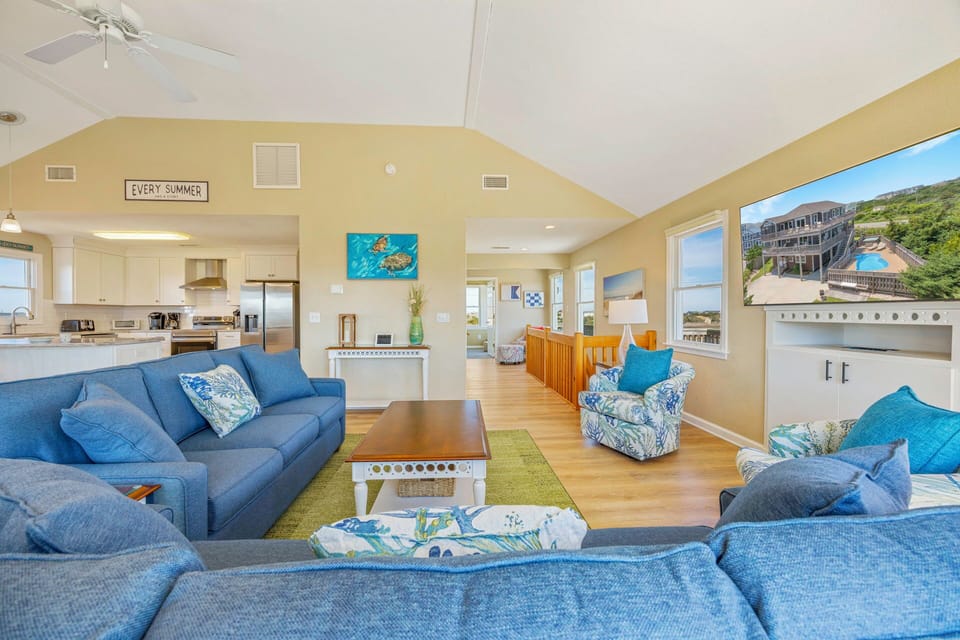 Sink into coastal comfort in your spacious living area, where ocean-blue furnishings and vaulted ceilings create the perfect gathering space.