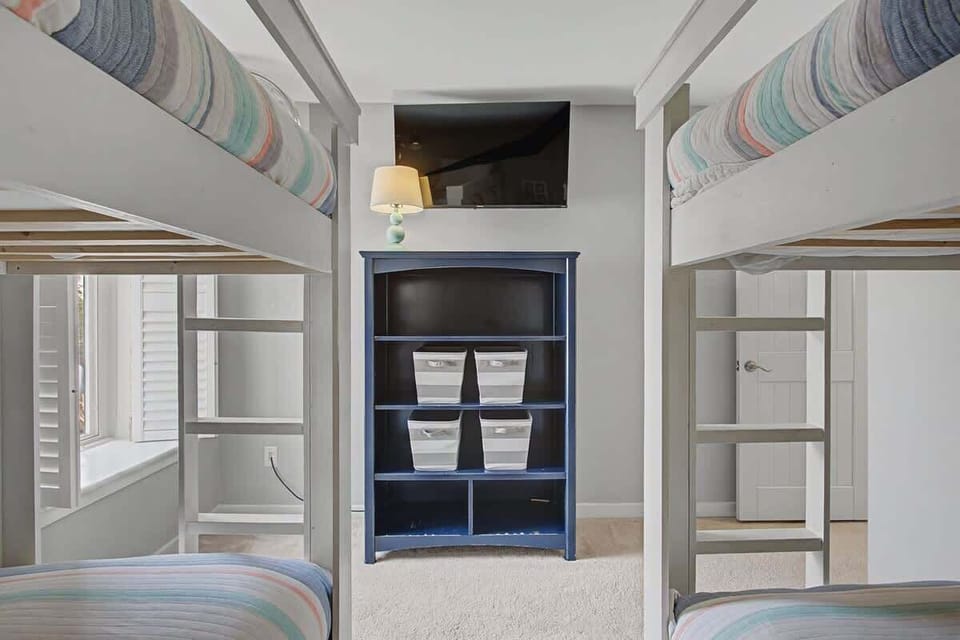 Your family will love this cheerful bunk room with four comfortable beds, organized storage, and a mounted TV for movie nights together.