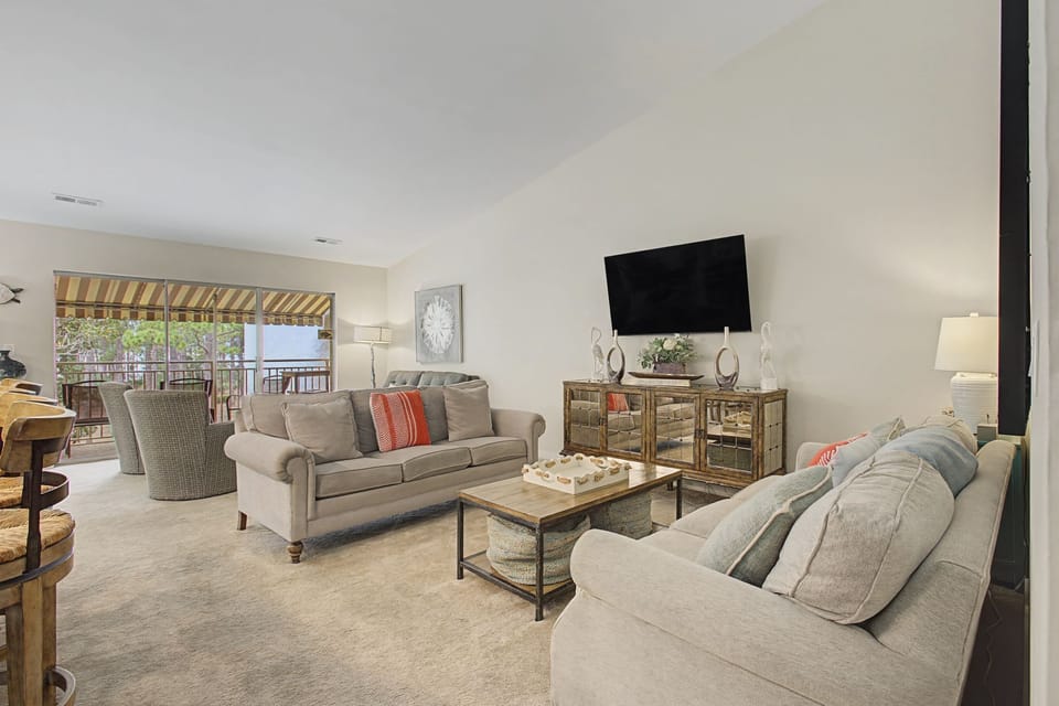 Sink into plush sofas in your spacious living room, where natural light streams through the patio doors and entertainment awaits on the large TV.