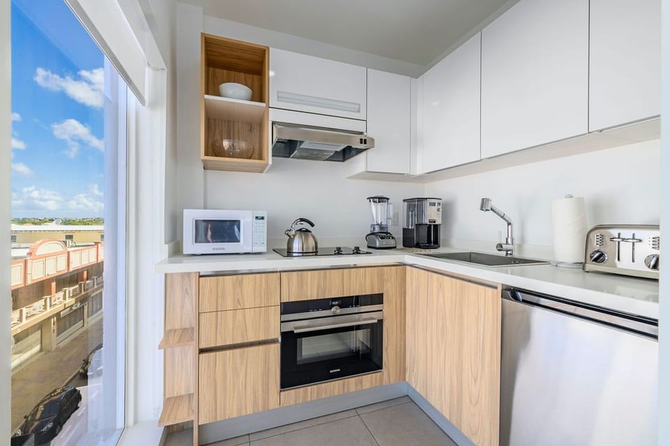 Your in-unit laundry closet features a stacked washer and dryer tucked neatly behind wood cabinetry, making it easy to keep fresh during your stay.