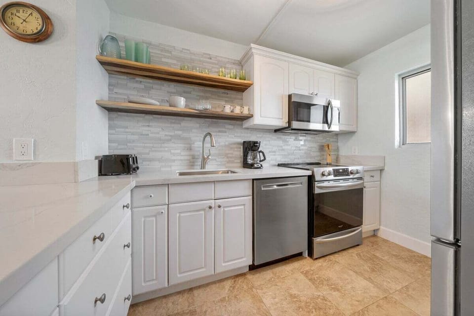 A bright, well‑appointed kitchen features white cabinetry, stainless appliances, and charming natural textures.