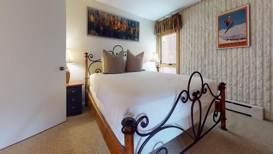 Slip into crisp white linens and let the soft glow of bedside lamps ease you into mountain dreams. Your cozy retreat awaits with charming vintage touches.
