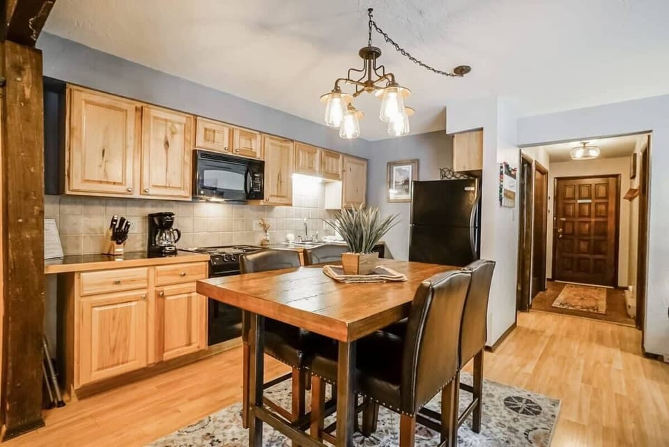 View of the dining area, fully-equipped kitchen, and front door