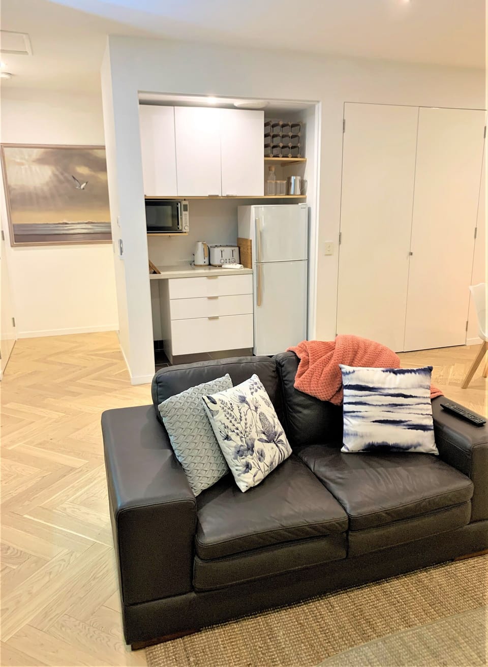 Comfy leather couch with kitchen and artwork in background