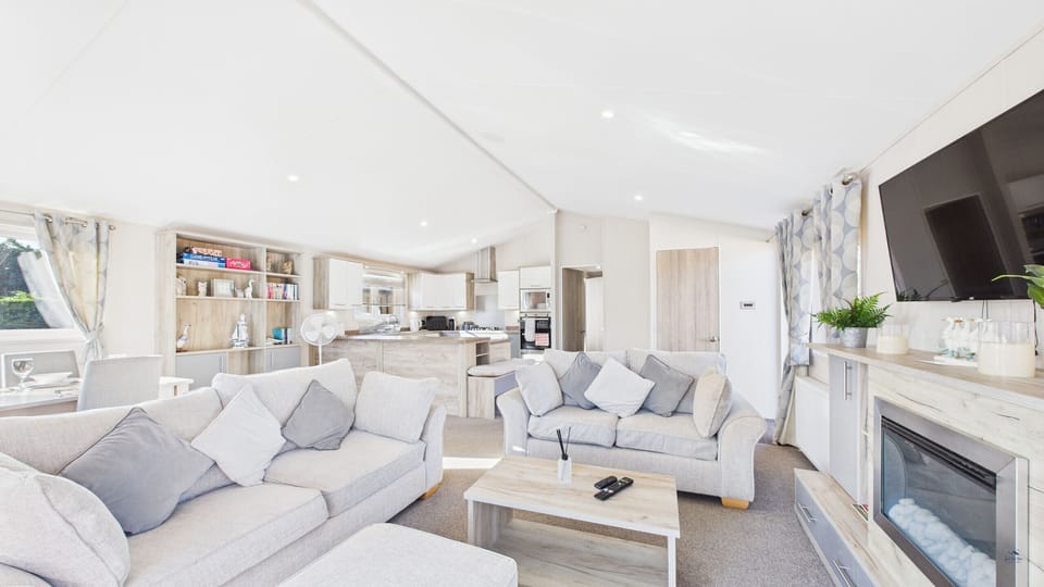 A wide-angle view of the spacious holiday lounge, featuring a comfy sofa and modern fireplace.