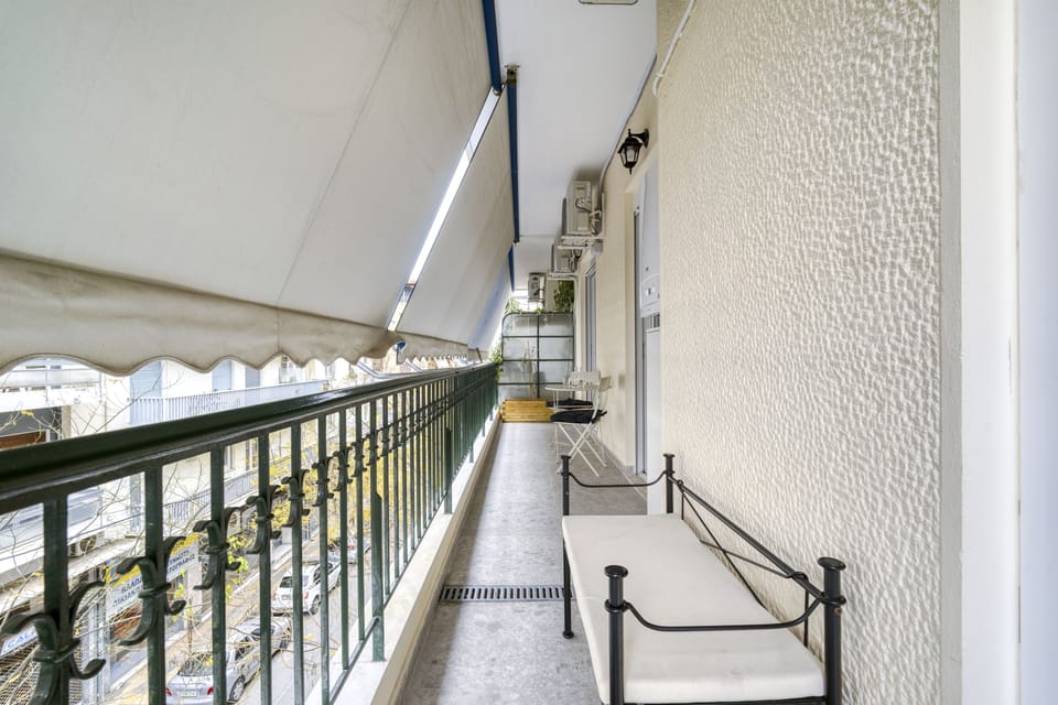Balcony the full length of apartment, featuring café table and chairs, bench.
