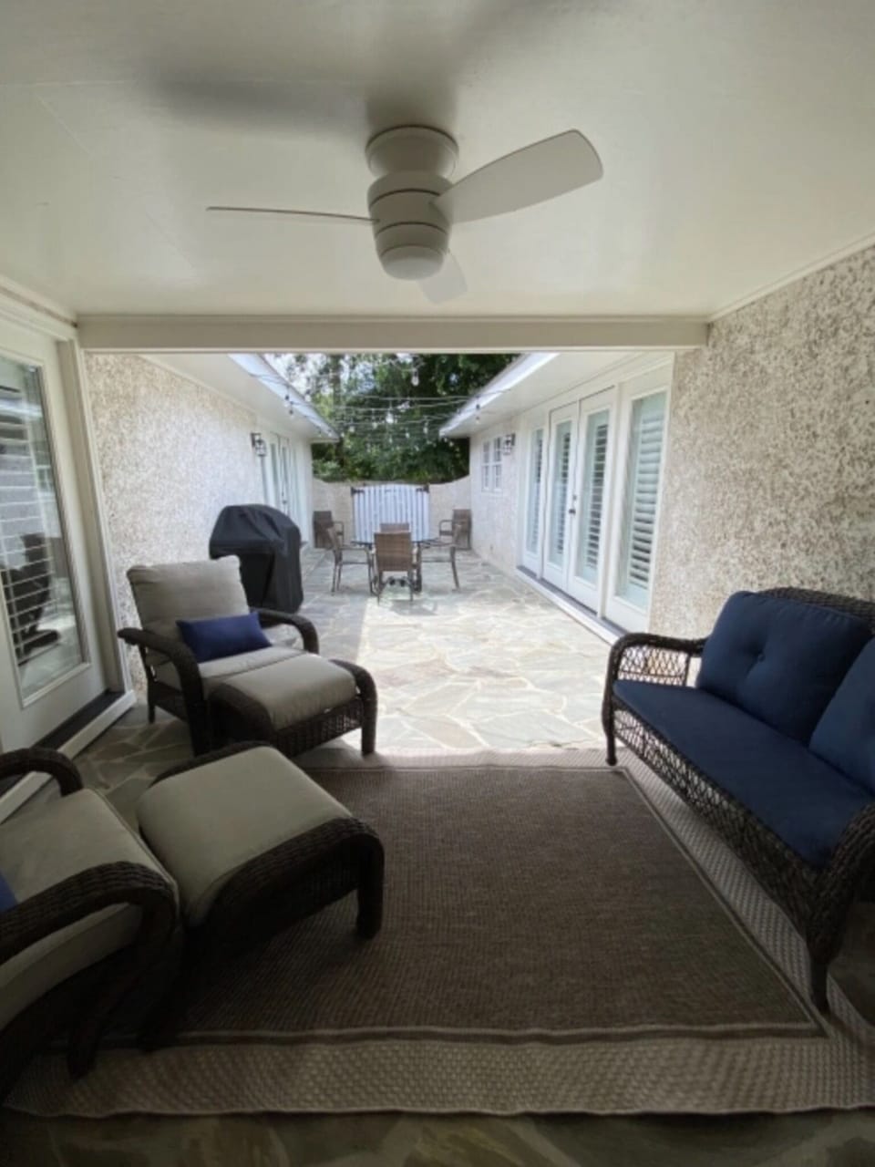 Partially covered back patio area with seating, dining, and large grill