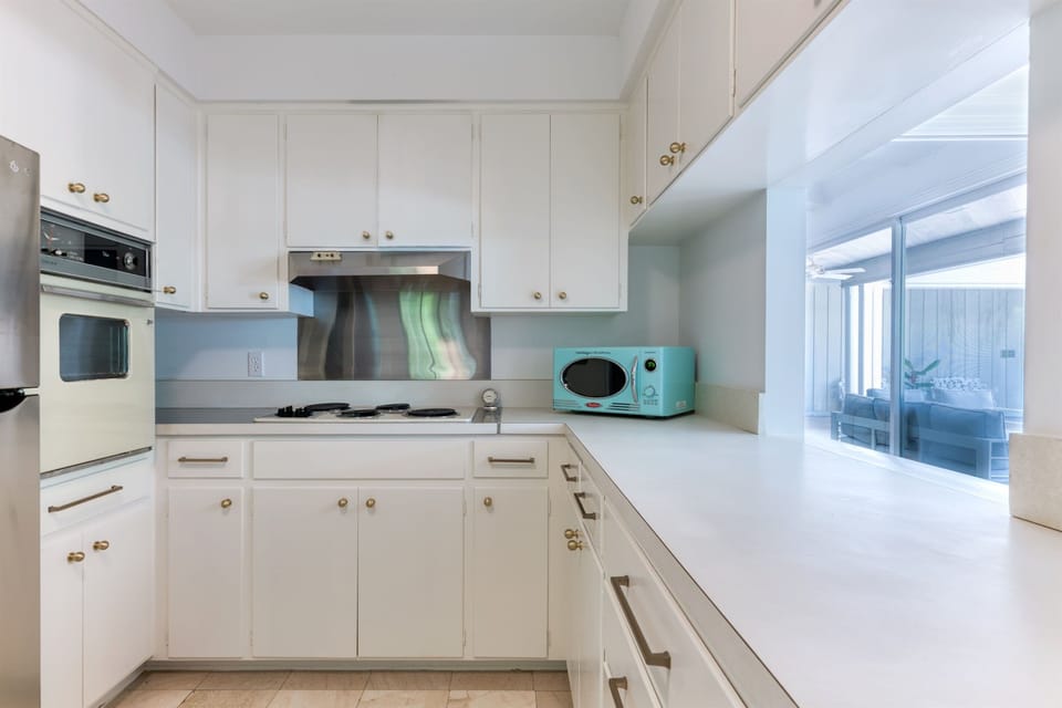 The impressive pure white Retro- style kitchen is complete with a new stainless steel fridge and a timeless "old school" stove top and oven. Funky Retro themed microwave and toaster bring it all together.