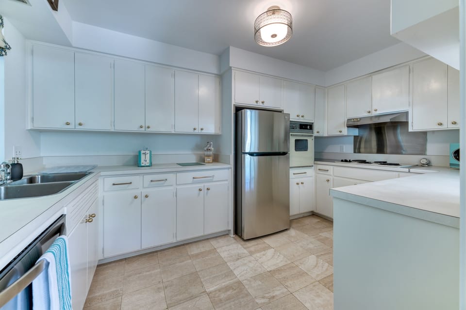 The impressive pure white Retro- style kitchen is complete with a new stainless steel fridge and a timeless "old school" stove top and oven. Funky Retro themed microwave and toaster bring it all together.