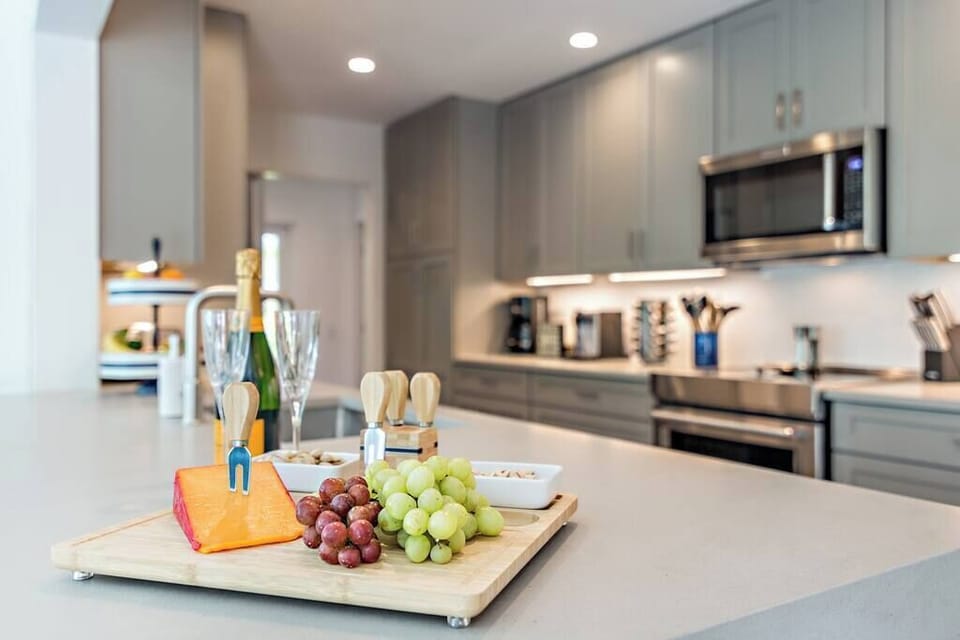 Modern kitchen with a spacious island featuring a cheese and grape platter for entertaining.