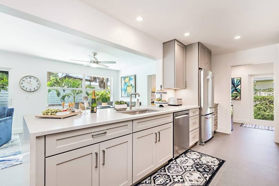 Modern kitchen with a large island and stainless steel appliances overlooking the living area.