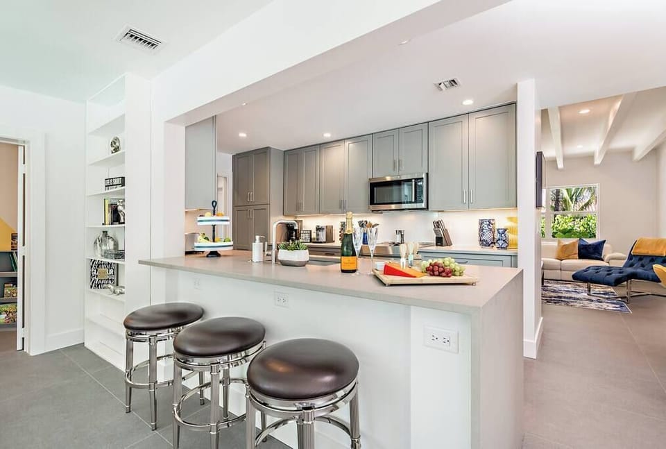 Modern kitchen with gray cabinetry and a breakfast bar with seating for three.