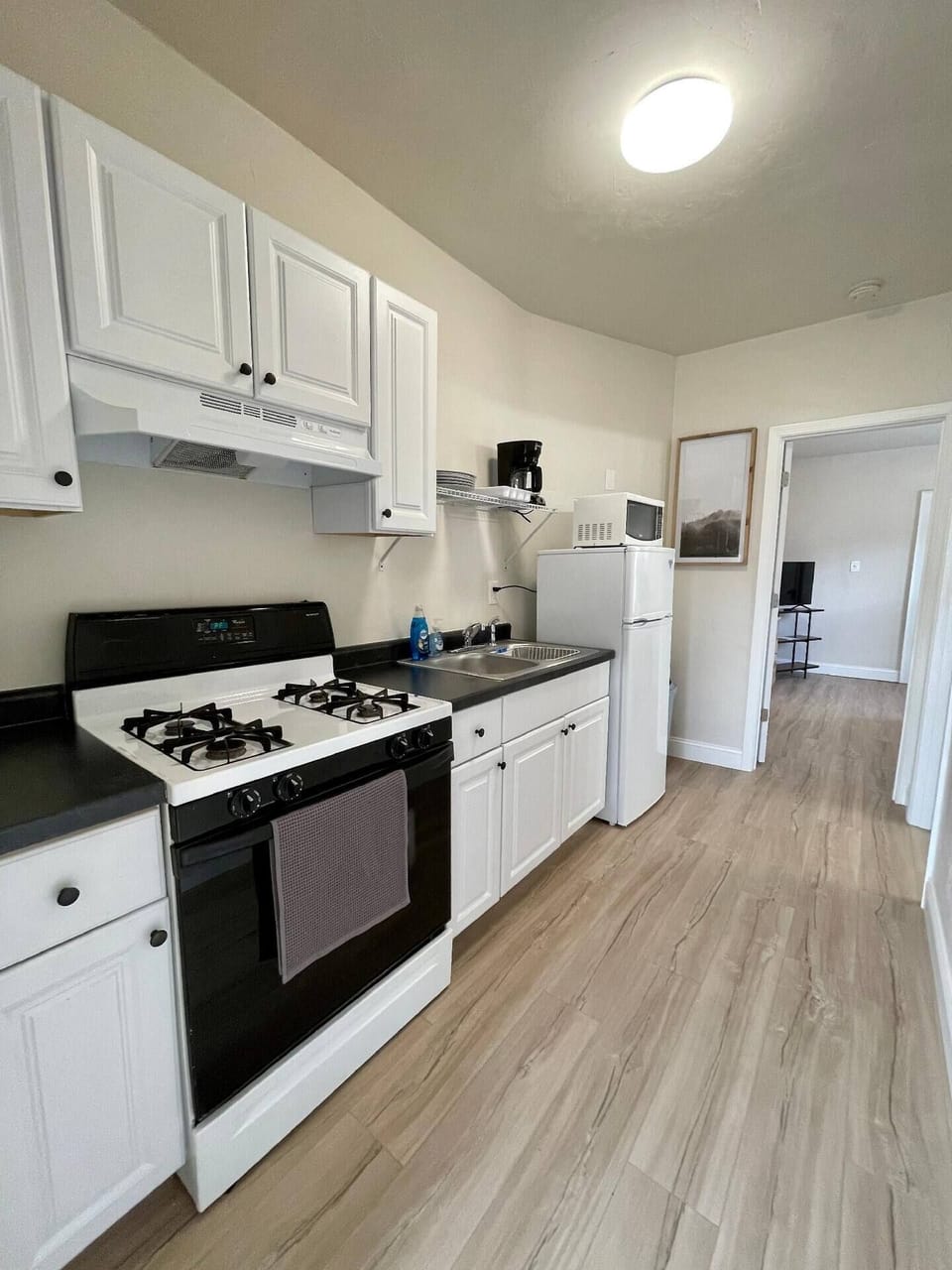 Galley style kitchen furnished with all the necessities to prepare meals like pots/pans, baking dishes, cooking knives, microwave and coffee maker