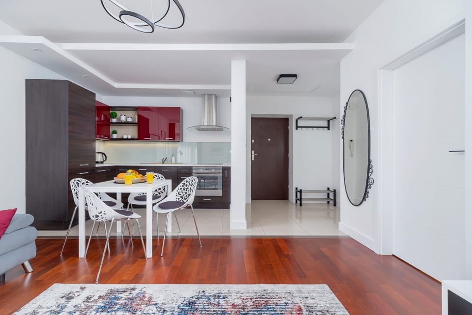 A  slightly wider angle of the living room, showcasing the patterned rug, sofa, and view of the hallway and dining table.
