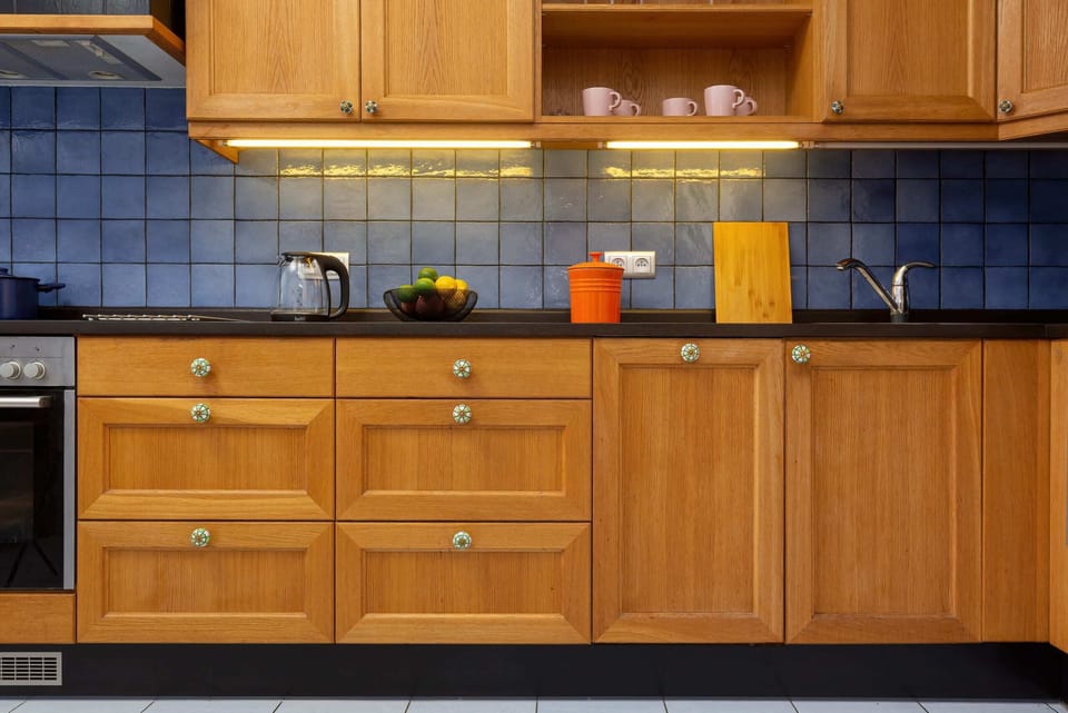 A kitchen featuring wooden cabinets, a tiled backsplash, and modern appliances, blending traditional and contemporary styles.