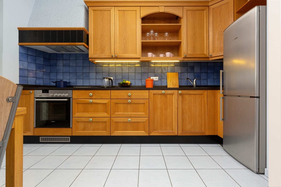A detailed view of the kitchen, showcasing its blue backsplash and polished wooden cabinets for a clean look.