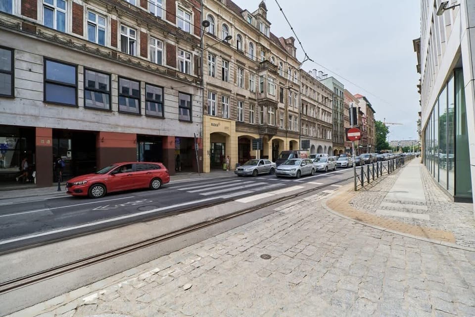 A vibrant street view showcasing shops and bustling city life with trams and cars in the foreground.