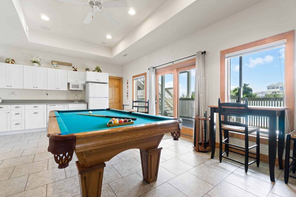 Game room with a pool table, bathed in natural light.