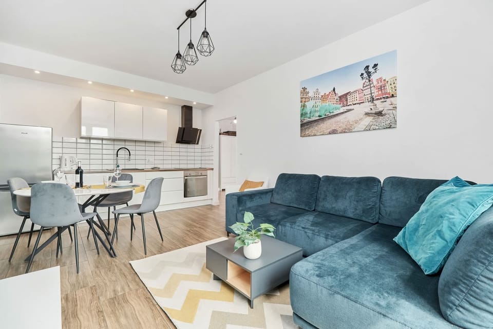 Living room with a corner sofa, TV, dining area and kitchenette.