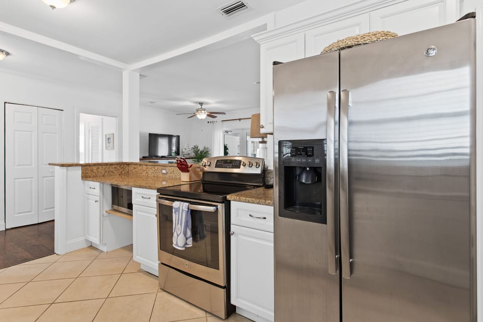 Kitchen with stove, microwave, stainless steel fridge with water dispenser.