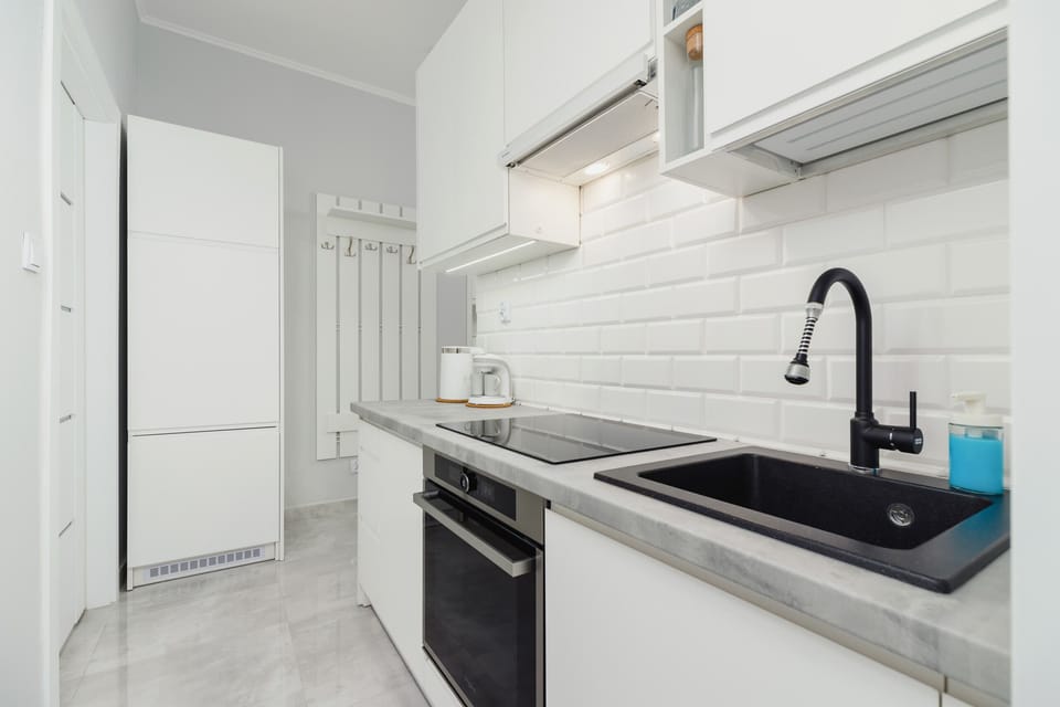 Modern, functional kitchen with black sink and appliances such as oven and hob.