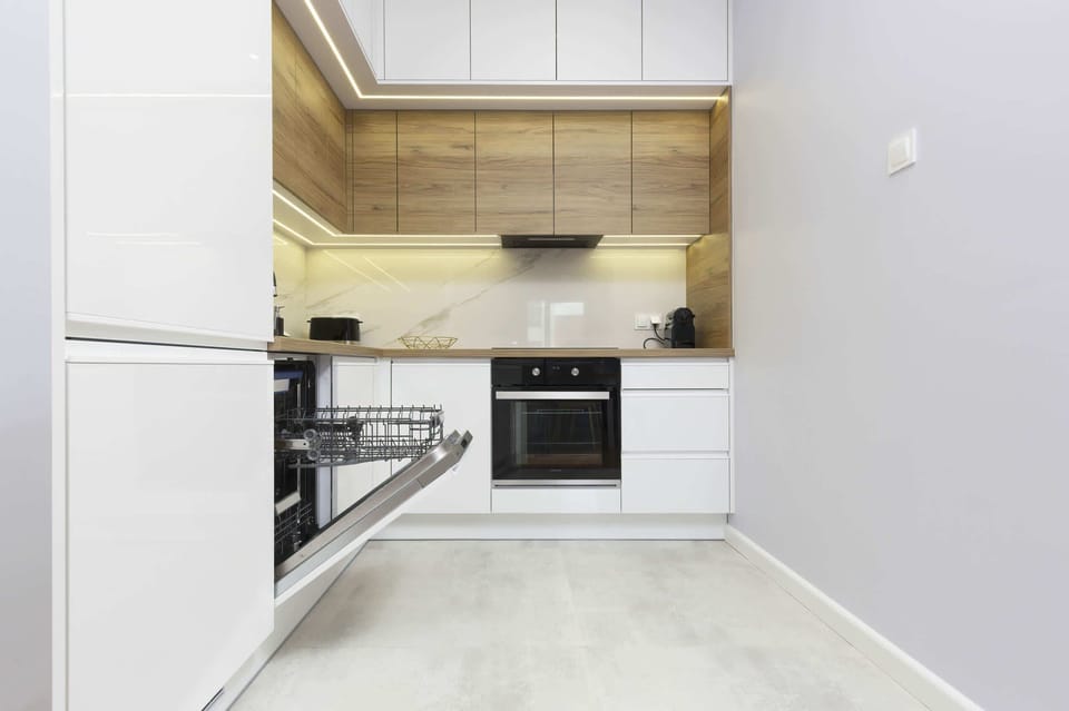 A high-end bathroom design with white marble finishes, a large mirror, and a built-in washer.