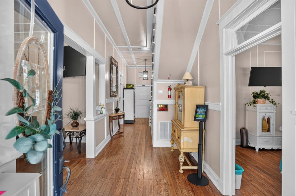 Elegant trim work, soaring ceilings, and original hardwood floors create a stunning entrance that reflects the rich history and inviting atmosphere of Hayes House.