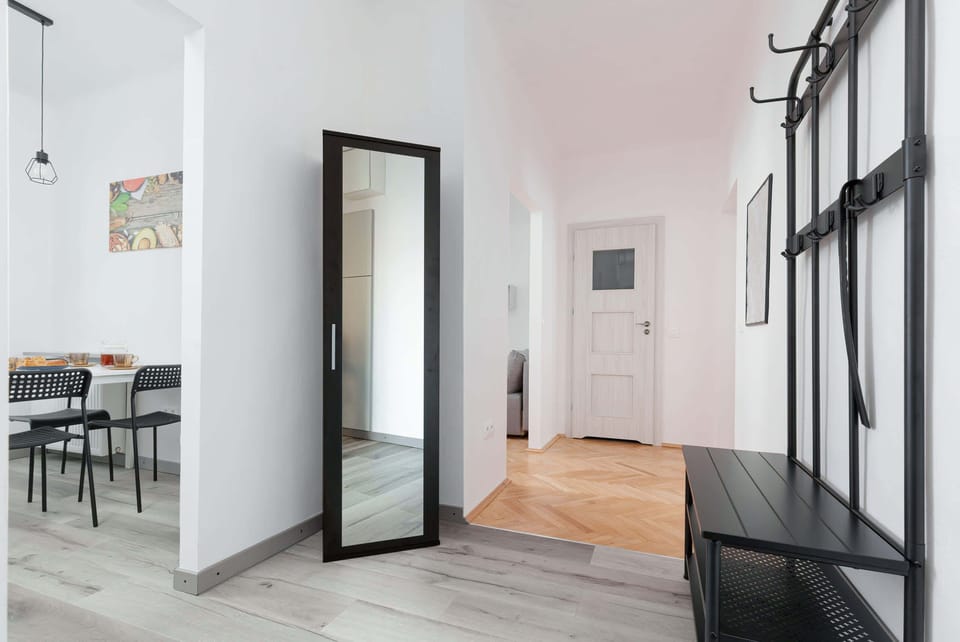 Bright hallway with black coat rack and large mirror.