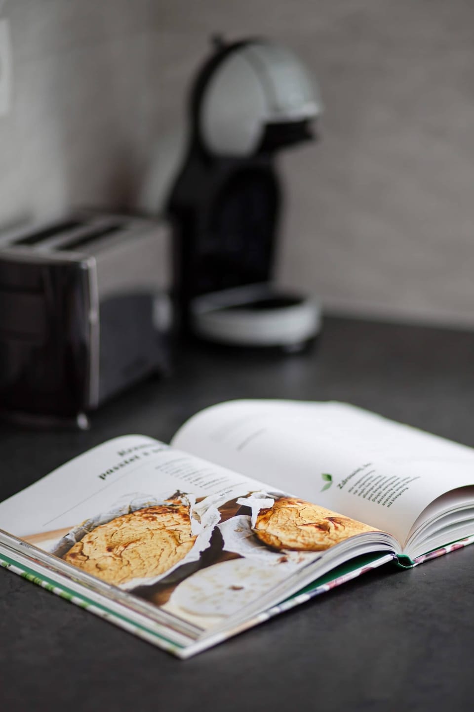 Close-up of cookbook, coffee machine and toaster.