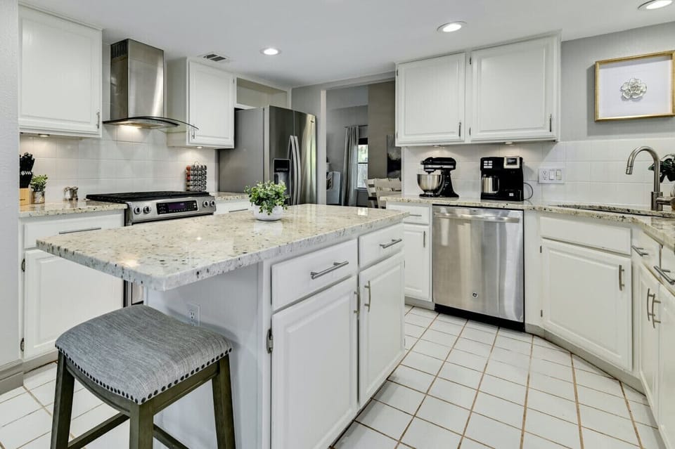 Bright white kitchen with granite island and stainless appliances makes cooking effortless during your elevated A Stay Above The Rest getaway.