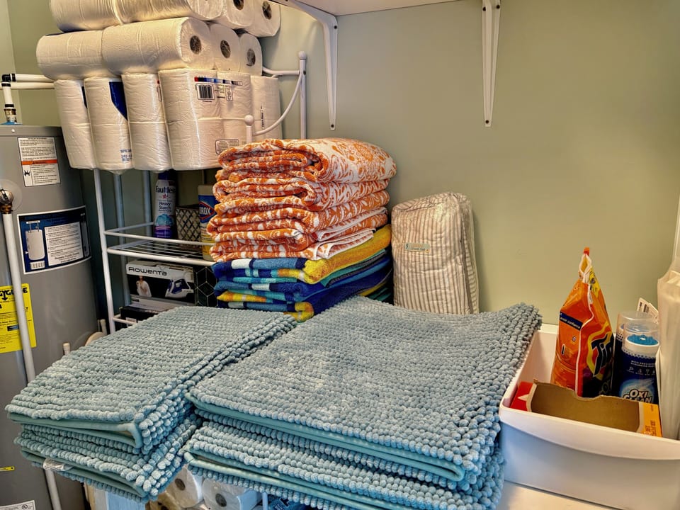 Detergent, beach towels, paper goods, linens & towels, & iron stored in laundry.