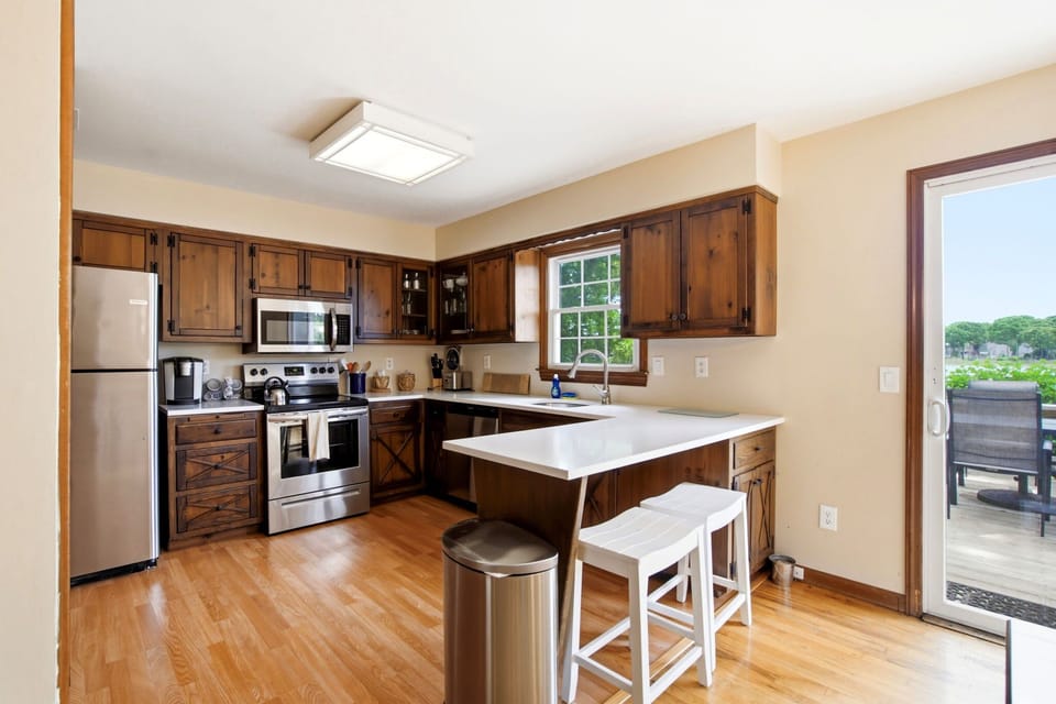 Kitchen with knotty pine cabinets, stainless appliances, bar seating