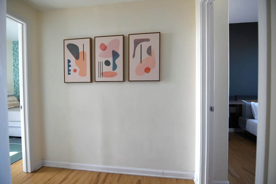 This light-filled hallway serves as a stylish crossroads, decorated with a contemporary abstract triptych that ties together the home's modern aesthetic. From here, you can transition easily between the different private retreats this home offers.