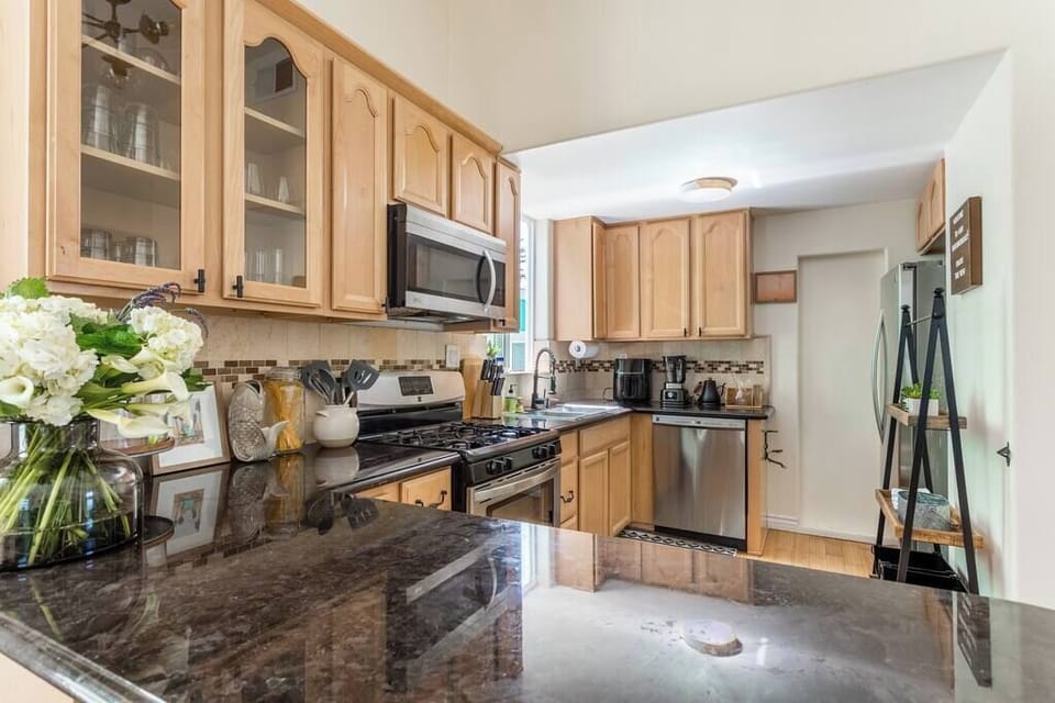 Prepare your favorite meals with ease in this sleek, modern kitchenette featuring cabinetry, a subway tile backsplash, and a tall wood-topped dining table.