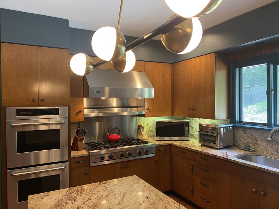 Chef's kitchen under the Stilnovo chandelier overlooking pool  and gardens.